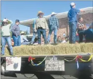  ?? Westside Eagle Observer/SUSAN HOLLAND ?? Members of the Gravette FFA Chapter announce they are “burn’in’ daylight” as they ride in the homecoming parade while another sign encourages the Lions to “beat those wolves.” They dressed in boots and jeans and rode on a float lined with bales of hay, making viewers feel they were down on the farm.