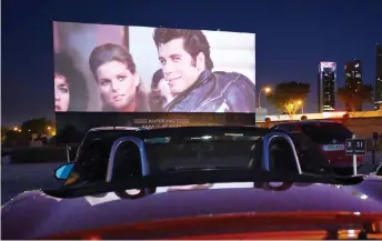  ?? — AFP photo ?? Cinema-goers in their cars attend the screening of the US musical romantic comedy film ‘Grease’ during the reopening of the Autocine Madrid Race drive-in cinema in Madrid.
