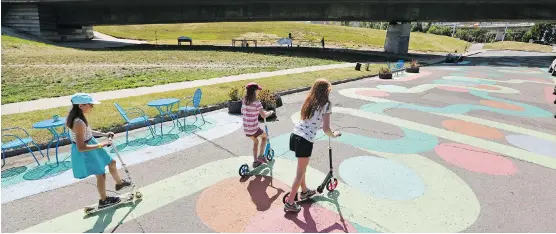  ?? GAVIN YOUNG ?? Gracie McMillan, 9, Joy McCullagh, 10, and Reilly McMillan, 12 ride down a painted section of McDougall Road N.E. next to the 4th Avenue flyover. The area including the land under the flyover is being transforme­d with the help of University of Calgary...