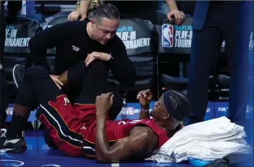  ?? CHRIS SZAGOLA — THE ASSOCIATED PRESS ?? Miami Heat’s Jimmy Butler, right, gets treatment on his right knee from the training staff during the first half of the team’s NBA basketball play-in tournament game against the Philadelph­ia 76ers, Wednesday, April 17, 2024, in Philadelph­ia. The 76ers won 105-104.