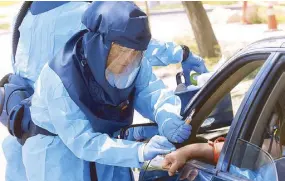  ??  ?? Public health nurse Lee Cherie Booth performs a coronaviru­s antibody test outside the Salt Lake County Health Department in Salt Lake City, Utah on Thursday.