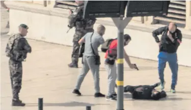  ??  ?? Police point a gun at suspect on the ground while soldiers secure the area after yesterday’s stabbings in Marseille
