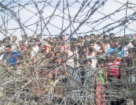  ?? AFP ?? In this 2018 file photo taken in Maungdaw district in Myanmar’s Rakhine state, Rohingya refugees gather behind a barbed-wire fence in a temporary settlement setup in a ‘no-man’s land’ border zone between Myanmar and Bangladesh.
