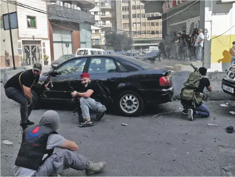  ?? AFP ?? Hezbollah and Amal gunmen take aim during a day of deadly violence that rocked the Lebanese capital on Thursday