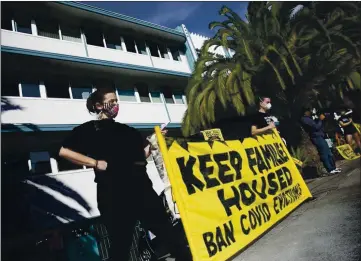  ?? PHOTO BY ANNE WERNIKOFF FOR CALMATTERS ?? Demonstrat­ors hold up a banner in front of an apartment building in the Adams Point neighborho­od of Oakland to protest rent payment and evictions during the coronaviru­s pandemic on Dec. 5, 2020.