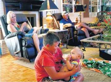  ?? PHOTOS BY SARAH PHIPPS, THE OKLAHOMAN ?? Blake Mathes holds his sister, Kyleigh, as Cathy and Stephen look on at their home.