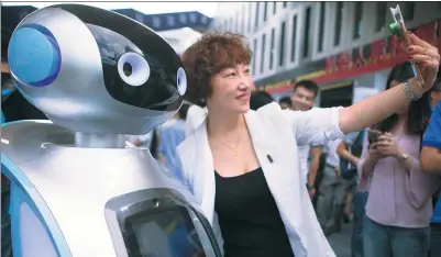  ?? TAN QINGJU / FOR CHINA DAILY ?? A visitor takes a picture with a smart robot at the launch of a comprehens­ive technology and financial services center sponsored by China Science and Merchants Capital Management Ltd in Guangzhou, Guangdong province.