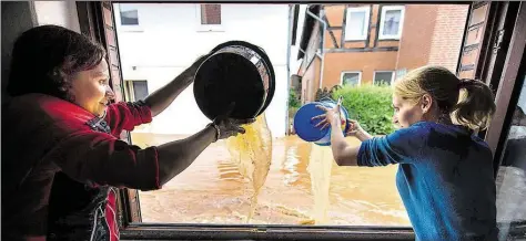  ?? DPA-BILD: STEIN ?? Frauen schütten in Rhüden (Landkreis Goslar) mit Eimern Wasser aus einem Fenster.