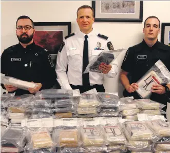  ?? DEAN PILLING ?? Canadian Border Services Agency director Guy Rook, centre, and CBSA agents display the nearly 100 kilograms of cocaine found in the cab of a truck that was stopped at the Coutts border crossing last weekend.