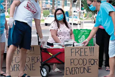  ?? AP Photo/Jon Gambrell ?? Feby Cachero Baguisa Dela Pena of Laguna, Philippine­s, hands out free food to those who need it June 3 in Dubai, United Arab Emirates. Dela Pena, a mother of three, is unemployed, but when she saw people lining up for free meals one night outside her building two weeks ago she decided to use whatever money her family had to help out the countless numbers of Filipinos and others who've lost jobs amid the coronaviru­s.