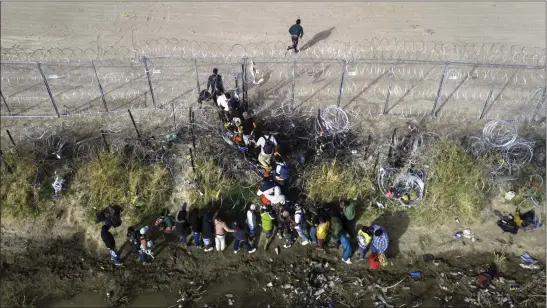  ?? JOHN MOORE — GETTY IMAGES ?? In an aerial view, immigrants pass through coils of razor wire while crossing the U.S.-Mexico border in March in El Paso, Texas.