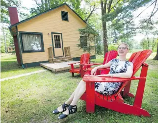  ??  ?? Fiona McKean relaxes in one of the signature red Muskoka chairs at the Opinicon Dining and Resort.