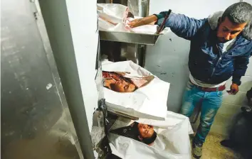  ?? AFP ?? A man looks at the bodies of three Palestinia­n boys killed in an Israeli air strike, at the morgue of Al Aqsa Hospital in Deir Al Balah in the central Gaza Strip on Sunday.