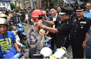  ??  ?? Shafie (second right) presents a new crash helmet to a rider during the launch of Ops Selamat 13 at Plaza Merdeka. At right is Sarawak Traffic Investigat­ion and Enforcemen­t Department chief Supt Alexson Naga Chabu.