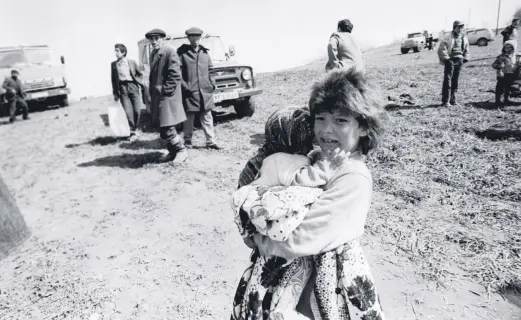  ??  ?? A girl holds her sister after fleeing the Armenian massacre of ethnic Azerbaijan­is in the town of Khojaly, Azerbaijan, February 1992. (Photos by AA)