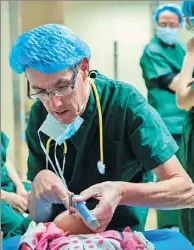  ?? HE PENGLEI / CHINA NEWS SERVICE ?? Marty Clayman, an anesthetis­t from the United States, prepares a young patient for surgery in Lhasa, Tibet autonomous region. Eighty children with cleft lips and palates will receive free treatment in the three-day “Smile Action” initiative.