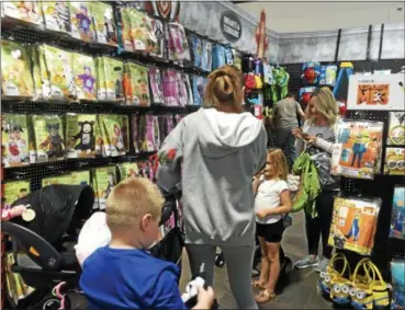  ?? KRISTI GARABRANDT — THE NEWS-HERALD ?? Britteny Weitzman shops for costumes for her children Jacob, 5 and Adalynn, 8 weeks. She is hoping to find a cat costume for Adalynn. Chelsea Wickman and daughter Eva, 6, look at a dinoasaur costume at Spirit Halloween in Mentor.