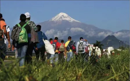  ?? MARCO UGARTE — THE ASSOCIATED PRESS ?? Central American migrants begin their morning trek as part of a thousands-strong caravan hoping to reach the U.S. border, as they face the Pico de Orizaba volcano upon departure from Cordoba, Veracruz state, Mexico, Monday. A big group of Central Americans pushed on toward Mexico City from a coastal state Monday, planning to exit a part of the country that has long been treacherou­s for migrants seeking to get to the United States.