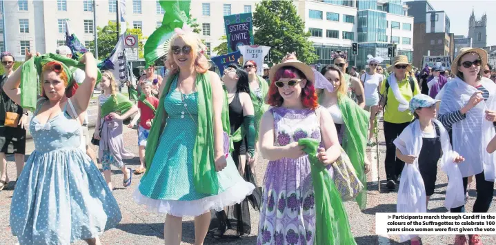  ?? Mark Lewis ?? &gt; Participan­ts march through Cardiff in the colours of the Suffragett­es to celebrate 100 years since women were first given the vote