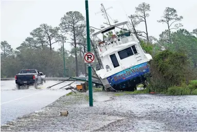  ?? GERALD HERBERT/AP ?? A boat rests near a road in Orange Beach, Ala., after washing ashore when Hurricane Sally moved through the area. The hurricane pushed a surge of ocean water onto the coast and dumped torrential rain.