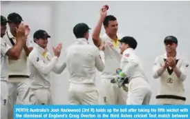  ??  ?? PERTH: Australia’s Josh Hazlewood (3rd R) holds up the ball after taking his fifth wicket with the dismissal of England’s Craig Overton in the third Ashes cricket Test match between England and Australia in Perth yesterday. — AFP