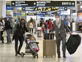  ?? DAVID SANTIAGO dsantiago@miamiheral­d.com ?? Travelers wearing protective face masks walking through Concourse D at the Miami Internatio­nal Airport on Sunday.