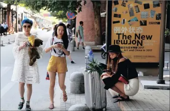  ??  ?? Chinese women walk past by a poster with the word “The New Normal” at an art district in Beijng, China. Credit rating agency Moody’s has cut its credit rating for China yesterday, citing slowing economic growth and rising debt.