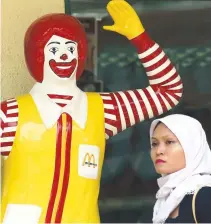  ??  ?? A WOMAN walks in front of a Ronald McDonald statue in Kuala Lumpur in this photo taken on Oct. 21, 2002.