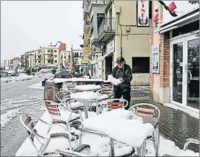  ?? ADRIÁ ROPERO / EFE ?? Un hombre quita la nieve de un bar en Pons, Lleida