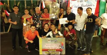  ??  ?? Mawan (fourth left) witnesses the handing over of the Champion trophy from Nait (third left) to Pebadas badminton team manager Simon Aleh.