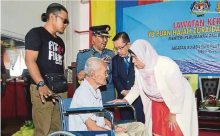  ?? PIC BY L. MANIMARAN ?? Housing and Local Government Minister Zuraida Kamaruddin (right) talking to Mohd Zin@Abdul Halim Din (in wheelchair), a retired fireman, during her visit to the Seri Manjung fire station in Manjung yesterday.