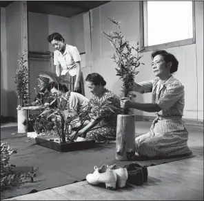  ?? © Paul Faris/Courtesy of Mary Ann Thurmond and Tim Faris ?? A class on ikebana — Japanese flower arranging — was one of the artistic activities at Rowher Relocation Center photograph­ed by Paul Faris. His photograph­s are on exhibit at the Butler Center for Arkansas Studies through Dec. 30.