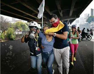  ?? Ariana Cubillos/Associated Press ?? » RESGATE Manifestan­tes carregam mulher desmaiada após respirar gás lacrimogên­eo em protesto em Caracas; caos em Barinas, Estado natal de Chávez, deixa quatro mortos