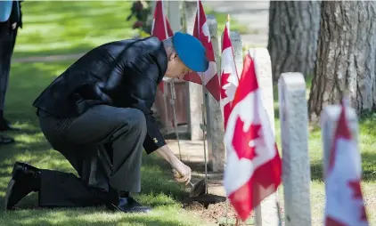  ?? Andrew Caballero -Reynolds ?? Newfoundla­nd peacekeepi­ng veteran Garry Best buries a UN hat badge at the grave of Cpl. Otto Redmond in the Dhekelia Cemetery in Cyprus. The soldier died in a jeep rollover in 1967 while on a peacekeepi­ng mission.