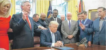  ?? EVAN VUCCI/AP ?? Religious leaders pray with President Donald Trump after he signed a proclamati­on for a national day of prayer on Sept. 1 of last year.