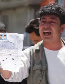  ?? Associated Press ?? Women cry at a hospital after they lost their relatives in the attack; Right; a man shows the ID paper of his relative outside a voter registrati­on centre which was attacked by a suicide bomber in Kabul on Sunday.