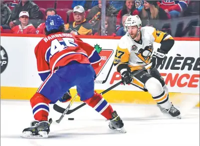  ?? MINAS PANAGIOTAK­IS / GETTY IMAGES / AFP ?? Bryan Rust of the Pittsburgh Penguins skates against Mark Barberio of the Montreal Canadiens during Wednesday’s NHL clash at Bell Centre in Montreal. The league is hopeful of staging preseason exhibition games in China this fall.