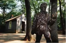 ??  ?? A statue of Henry David Thoreau stands outside a replica of his cabin near the shores of Walden Pond in Concord, Mass.