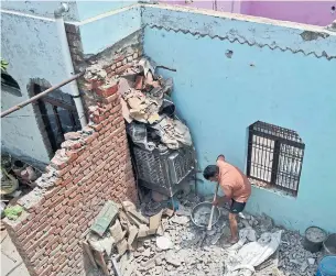  ?? PAWAN SHARMA/THE ASSOCIATED PRESS ?? A man cleans fallen concrete after walls and the roof of his house collapsed during the storm.