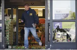  ?? MARK HUMPHREY — THE ASSOCIATED PRESS ?? An FBI agent steps over soft drink bottles and broken glass as he walks through a damaged entrance at a Kroger grocery store in Colliervil­le, Tenn., on Friday.