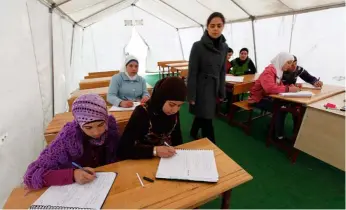 ??  ?? Una voluntaria de cooperació­n internacio­nal da clase a niñas sirias en el campo de refugiados de Boynuyogun, en Turquía, junto a la frontera con Siria.