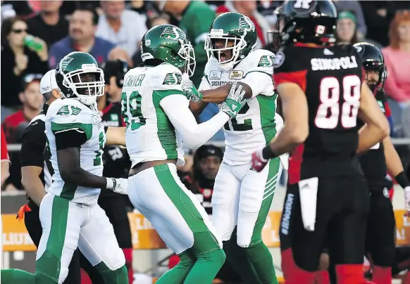  ?? THE CANADIAN PRESS ?? Roughrider­s teammates congratula­te Duron Carter (No. 89) after he registered the second pick-six of his CFL career on Thursday night against the Ottawa Redblacks.