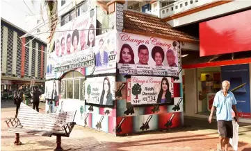  ??  ?? This file photo shows a resident walking past election posters in the Fijian capital of Suva. — AFP photo