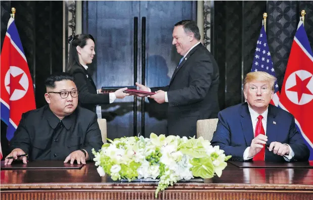  ?? KEVIN LIM / AFP / GETTY IMAGES ?? North Korea’s leader Kim Jong Un keeps an eye on U.S. President Donald Trump while documents are exchanged behind them.