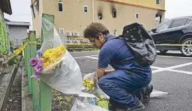  ??  ?? A man places flowers outside the Kyoto Animation Studio building consumed in an arson attack yesterday.