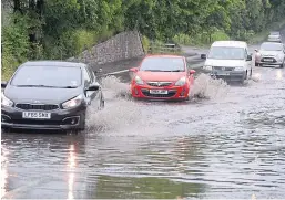  ?? Picture: Ken Jack. ?? Cars negotiate floodwater on the A921 at Dalgety Bay in Fife.