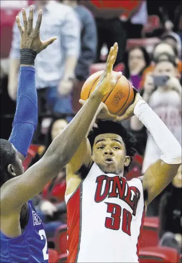  ?? BENJAMIN HAGER/LAS VEGAS REVIEW-JOURNAL ?? UNLV guard Jovan Mooring banks in a 3-pointer over Air Force’s Trevor Lyons as time expires in regulation, tying the game at 58. Mooring hit 7 of 14 3-point tries and scored 30 points as the Rebels gained an 87-85 double-overtime victory Saturday at...
