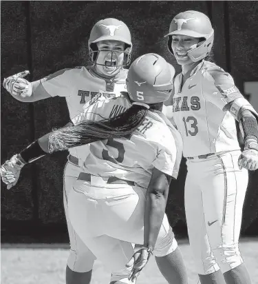  ?? Sarah Phipps / Associated Press ?? UT’s Taylor Ellsworth, left, and Shannon Rhodes (13) celebrate Jordan Whitaker’s home run Saturday in Stillwater, Okla. Whitaker, a freshman, broke a 1-all tie and her shot preceded another Longhorns homer.