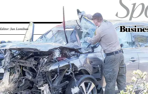 ??  ?? A LAW enforcemen­t officer looks over Tiger Woods’s damaged vehicle. AP