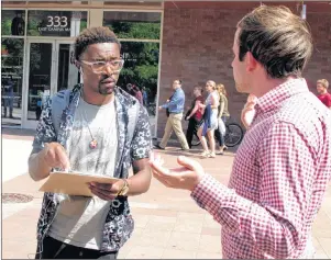  ?? AP PHOTO ?? In this Aug. 30 photo, University of Wisconsin freshman Kellen Sharp, left, gets informatio­n about registerin­g to vote from NextGen America worker Sean Manning, right, in Madison, Wis. Sharp says he’s excited to vote. He and others at the Madison event think young people are more energized than ever.